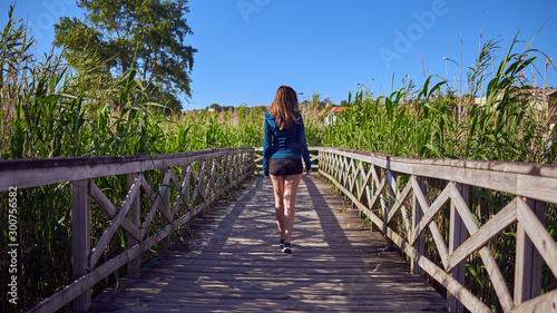 Young woman in sports clothes walking by a wooden walkway in Playa America, Vigo