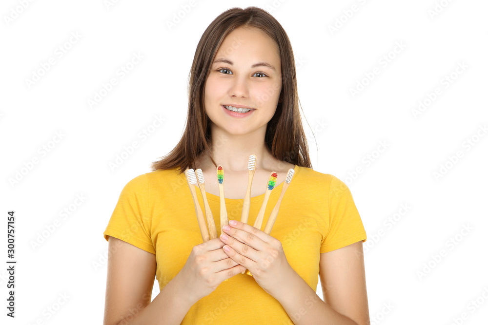 Young girl with dental braces holding toothbrushes on white background Young girl with dental braces holding toothbrushes on white background