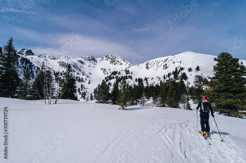 Ski alpinist ascending a snow slope in the alps. Winter alpine mountain landscape and ski touring adventure activity. Ski alpinism in the Alpine mountain area, Europe.