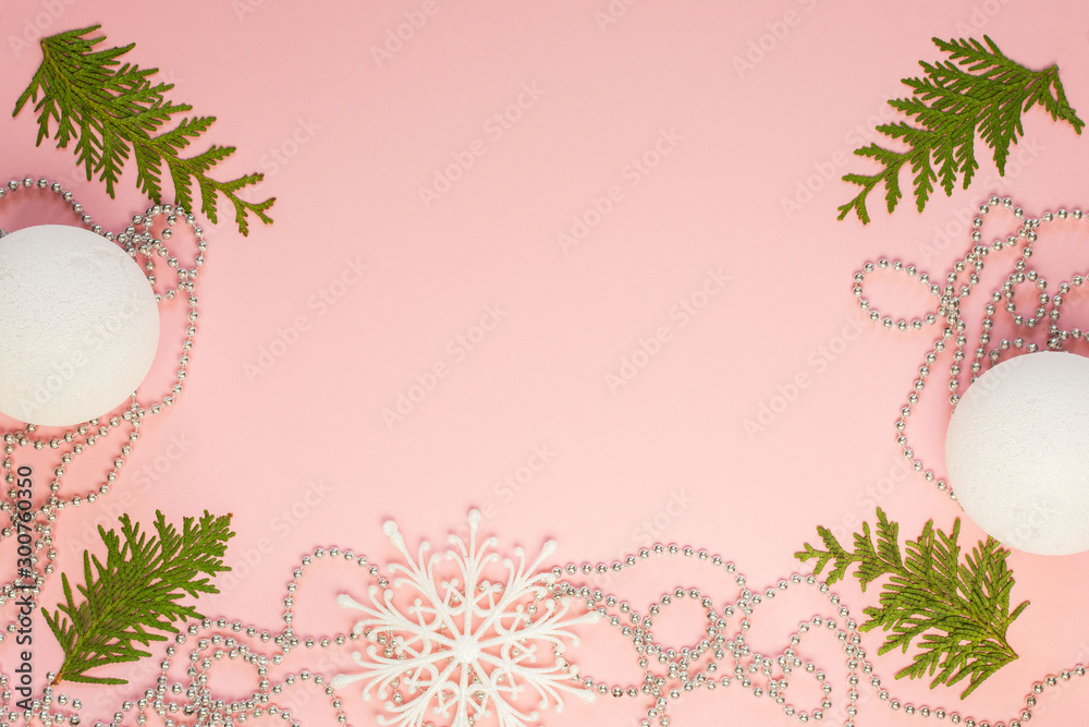 Holiday christmas background, fir branches and silver decorative beads, white snowflakes and christmas balls on pink background, flat lay, top view