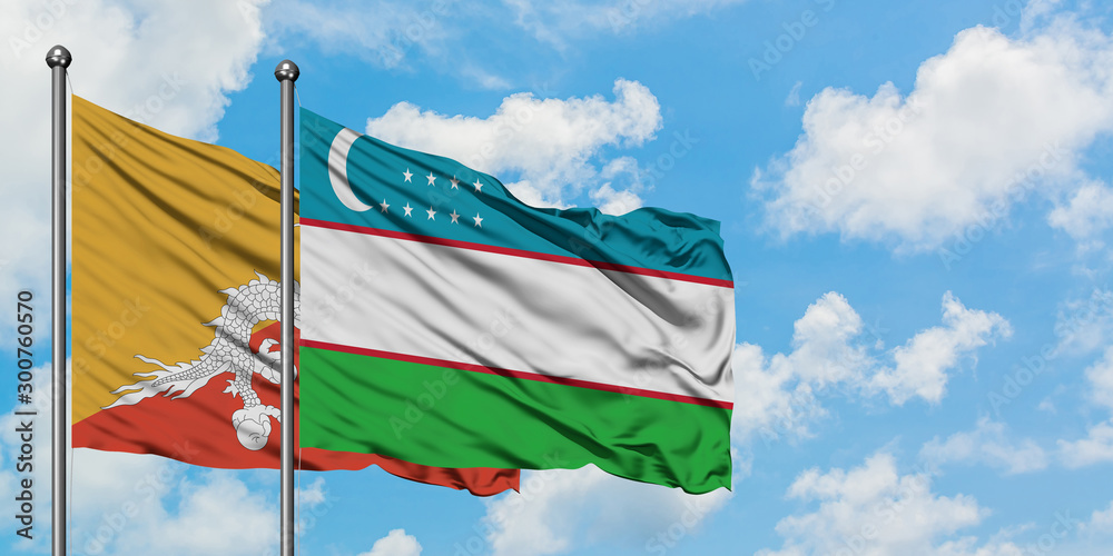 Bhutan and Uzbekistan flag waving in the wind against white cloudy blue sky together. Diplomacy concept, international relations.