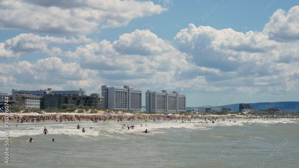 Big waves on the sea beach, people swimming in the background. Big waves on the sea beach, people swimming in the background.