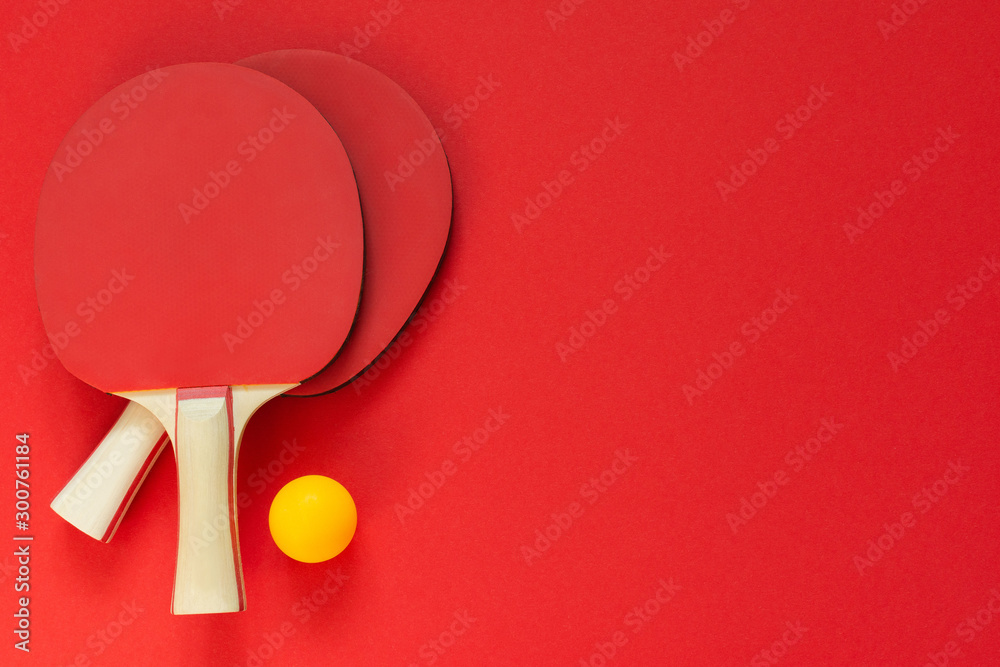 Red tennis ping pong rackets and orange ball isolated on a red