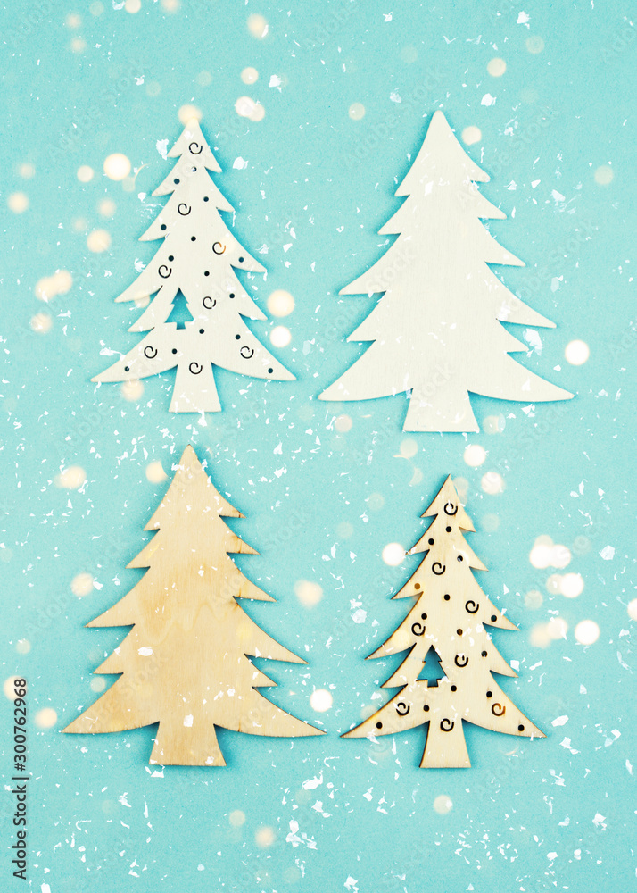 Wooden decorative Christmas trees on a blue background with sparkles. Hanging Christmas decorations.