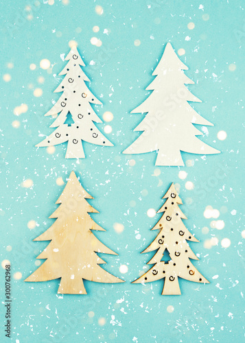 Wooden decorative Christmas trees on a blue background with sparkles. Hanging Christmas decorations. © Татьяна Креминская