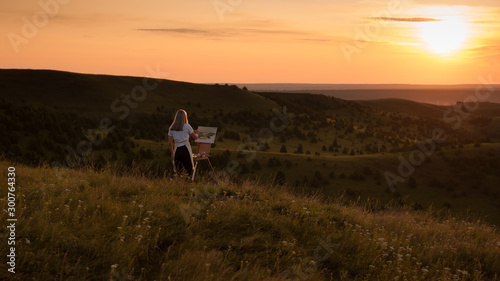 The artist paints a picture outdoors in the early sunny morning. Painting in nature.	