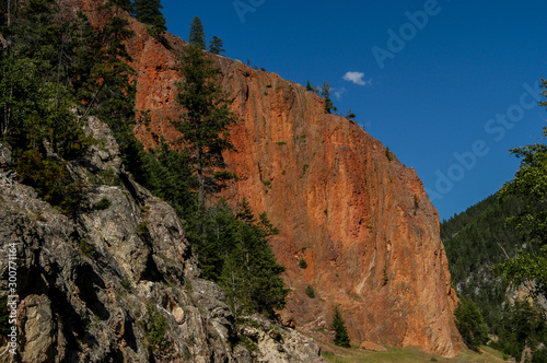 Tall red orange sheer canyon walls against a blue sky near Radium Hot Springs, Kootenay National Park in British Columbia, Canada