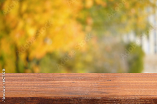 Empty table on the background of the autumn garden. Blurred background. Free space for your products