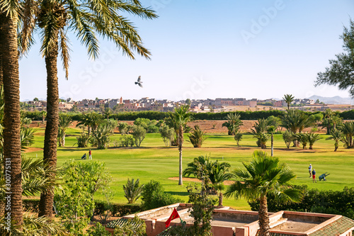 View of Marrakech from a golf resort with green fields and palms in Morocco