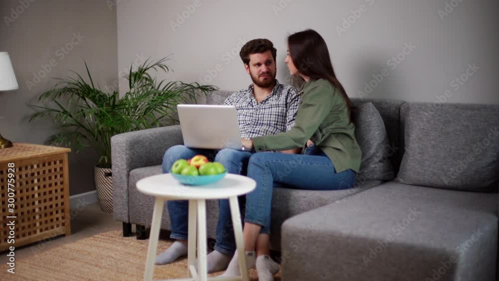 Lovely positive young couple is using laptop for e-commerce doing online shopping. Shooting in slow motion. Lovely positive young couple is using laptop for e-commerce doing online shopping. Shooting in slow motion.