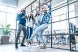 Merry Christmas and Happy New Year 2020. Multiracial young creative people are celebrating holiday in modern office. Group of young business people are drinking champagne in coworking. Successful