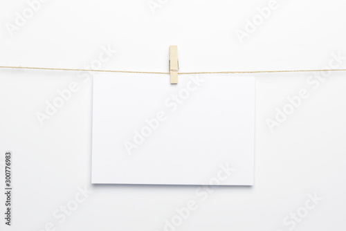 Pinza colgando de una cuerda con una tarjeta en blanco sobre fondo blanco photo