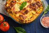 Italian lasagna, on a blue wooden background. Culinary background, Italian recipe book, delicious food. With space for design, top view.