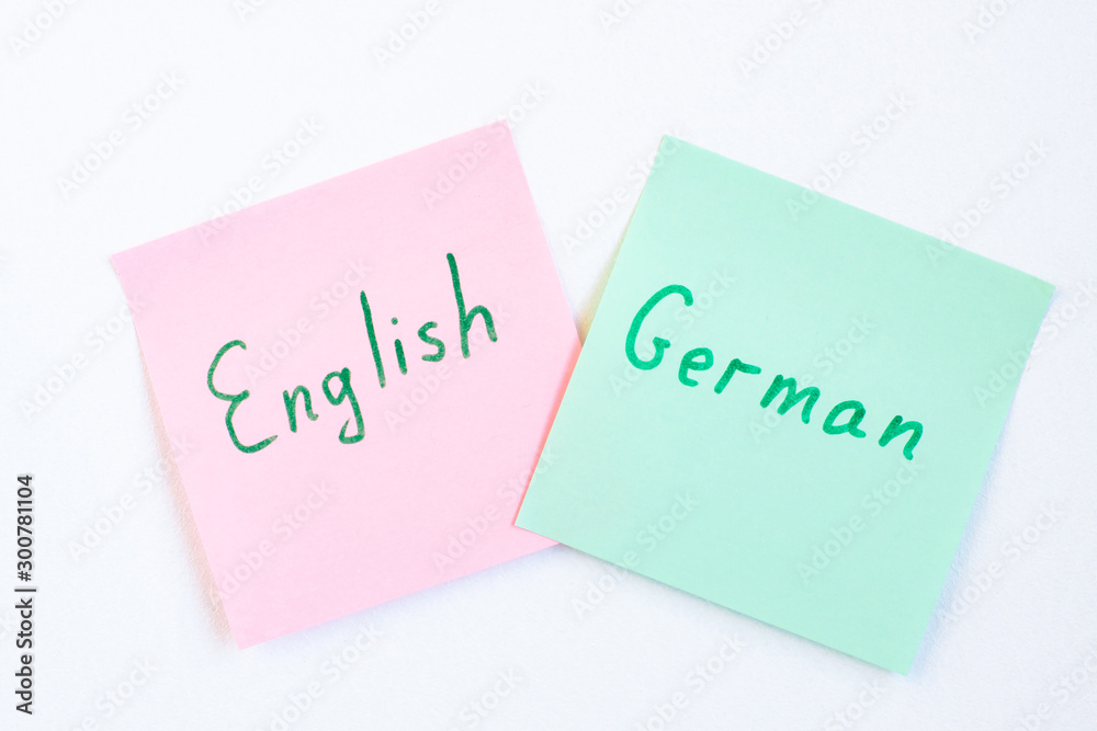 Top view flat lay of two languages english and german which written on the reminder notepaper of different colors Top view flat lay of two languages english and german which written on the reminder notepaper of different colors