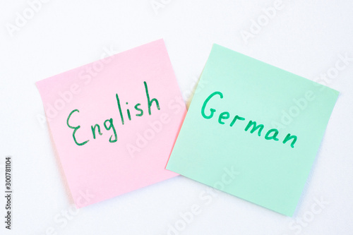 Top view flat lay of two languages english and german which written on the reminder notepaper of different colors