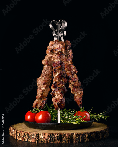 Foto Tower of shish kebab skewers on cast iron served with rosemary and tomatoes
