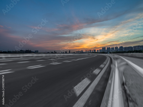 Asphalt road and the beautiful urban skyline at sunset © hallojulie