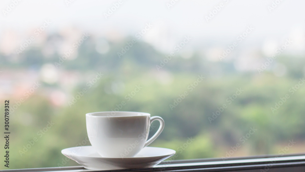 White cup coffee on the window view city blur background, wake up concept.