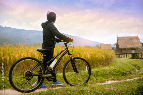 Woman standing with bike looking at rice field , Bike at the summer sunset in the nature. Bicycle and ecology lifestyle concept.
