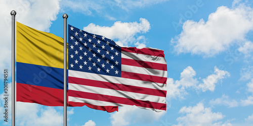 Colombia and United States flag waving in the wind against white cloudy blue sky together. Diplomacy concept, international relations.