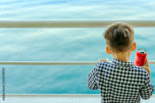Asian boy stands on baluster of ferry for relaxing and look at the ocean and island