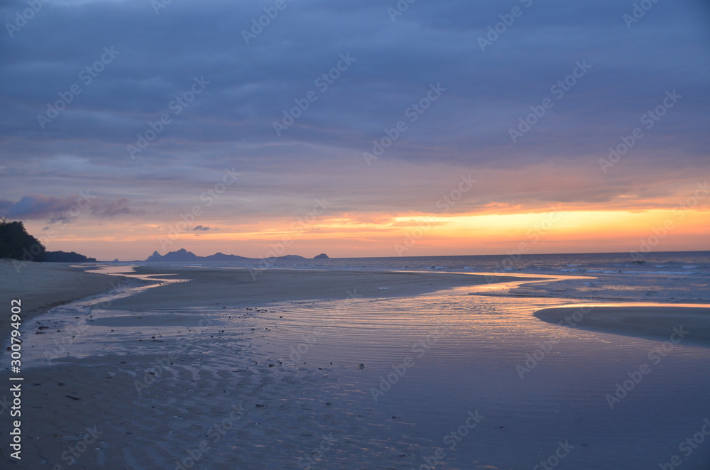 A threatening stormy but picturesque tropical orange and grey coloured cloudy coastal sunrise seascape.