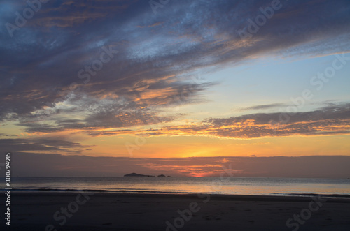 Dawn beauty  picturesque tropical orange coloured stratocumulus cloud coastal sunrise seascape in a blue sky.