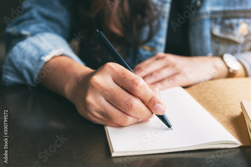 Closeup image of a woman writing on a blank notebook on the table