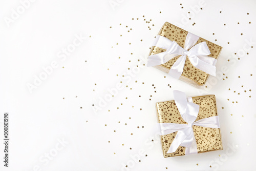 Golden christmas gift boxes and confetti on white background.