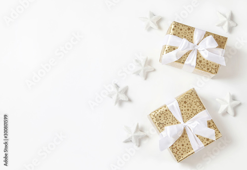 Golden christmas gifts with white ribbon and snowy stars.