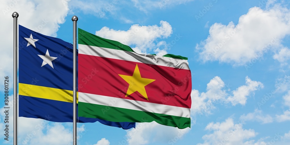 Curacao and Suriname flag waving in the wind against white cloudy blue sky together. Diplomacy concept, international relations.