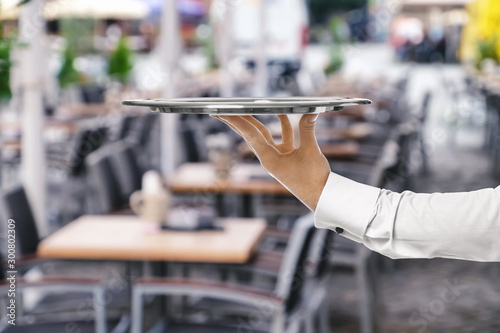 Waiter with empty tray in outdoor cafe