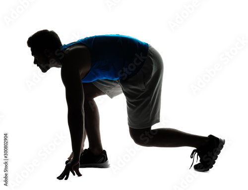 Silhouette of sporty young man in crouch start position on white background