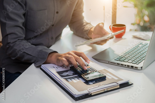 Businessman working on desk office with using a calculator to calculate the numbers, finance concept in office.
