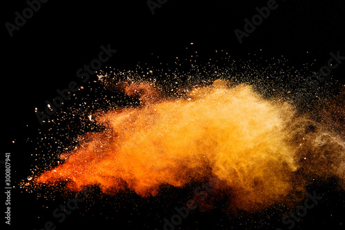 Abstract orange powder explosion isolated on black background.