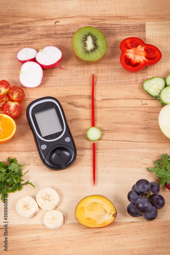 Glucose meter with fruits and vegetables in shape of clock, healthy eating for dinner concept Glucose meter with fruits and vegetables in shape of clock, healthy eating for dinner concept