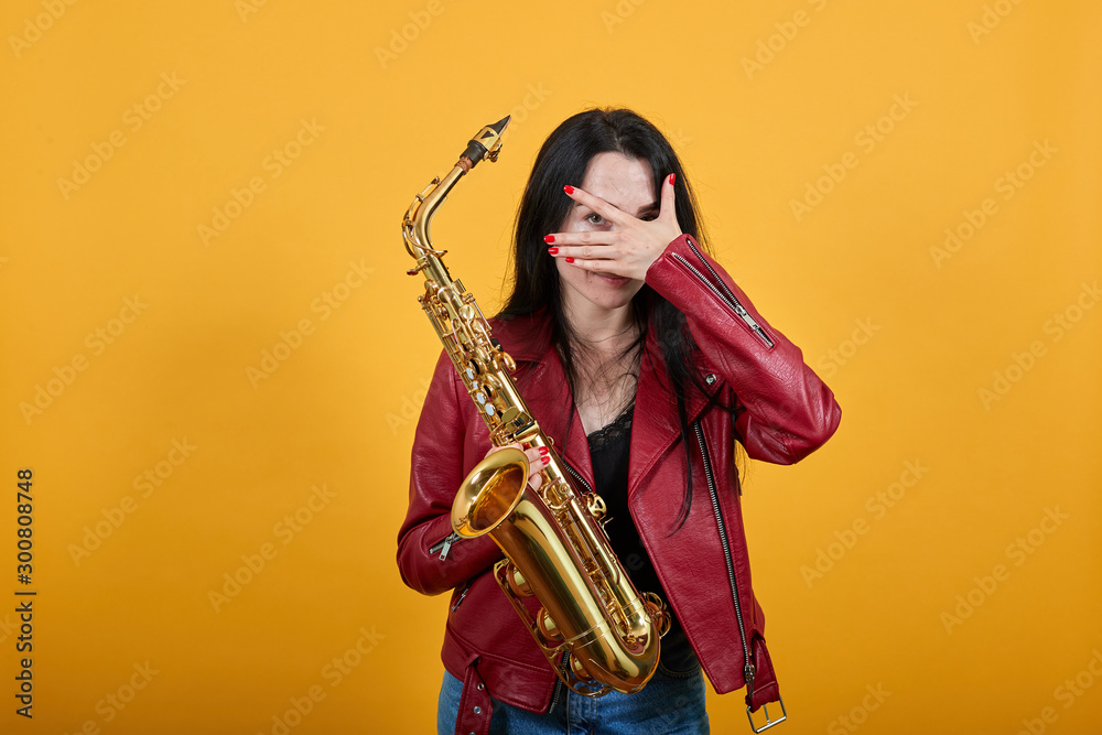 Naklejka premium Young brunette woman girl in casual clothes posing isolated on yellow wall background studio portrait. People sincere emotions lifestyle concept. Cover eyes with hand