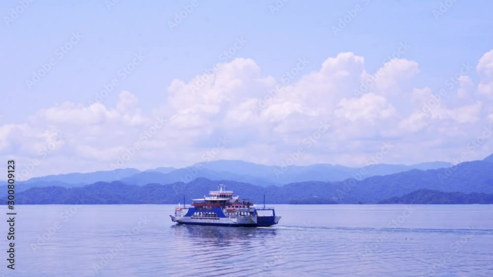 Ferry swimming into the Distance with Mountains on the Horizon in Costa Rican Landscape on Sunny Day with cloudy Sky Ferry swimming into the Distance with Mountains on the Horizon in Costa Rican Landscape on Sunny Day with cloudy Sky