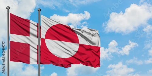 Denmark and Greenland flag waving in the wind against white cloudy blue sky together. Diplomacy concept, international relations.
