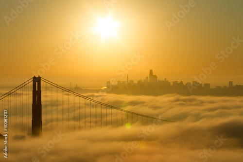 Golden Gate Bridge sunrise with low fog and city view