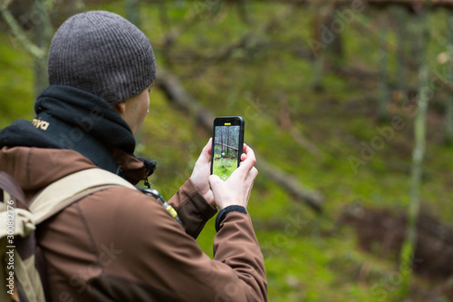 City Cesis, Latvia republic. The photographer is still photographing the forest landscape with phone. 2. november 2019.