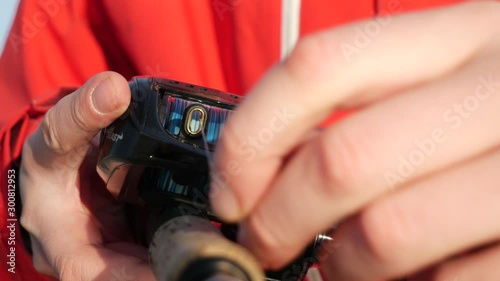 front weiw of fisherman prepares bait casting reel, rod, equipment, line. close up. photo