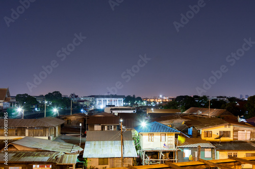 Beautiful rooftop view of cityscape of old time houses in crowded community and buildings with clear night sky in Bangkok. Dark, quiet an calm urban area.