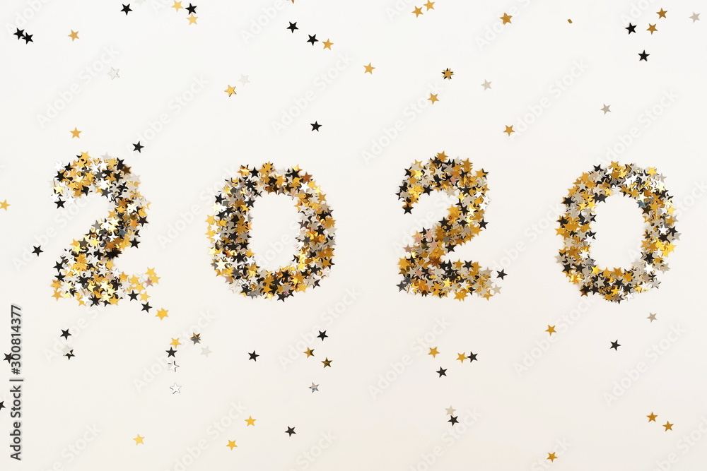 Christmas background. digits 2020 new year from gold black stars sparkles glitter on white background top view Christmas background. digits 2020 new year from gold black stars sparkles glitter on white background top view