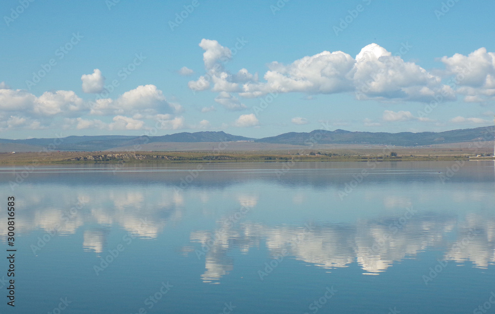Lake in the mountains with forest. Wide-angle image of a lake with mountains in the background and reflections in the water. Beautiful scenery. Lake in Transbaikalia.