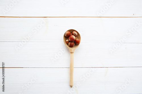 Hazelnuts in spoon on white wooden table with clipping path