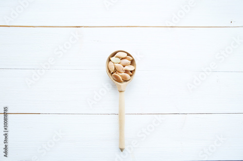 Pumpkin seeds in spoon on white wooden table with clipping path