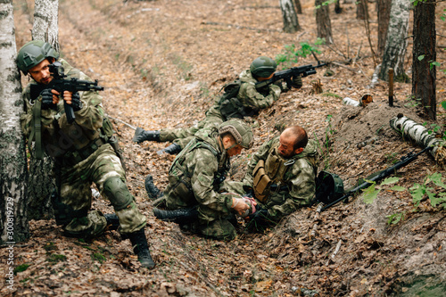 Bandaging a wounded soldier. A group of soldiers in defense of their positions.