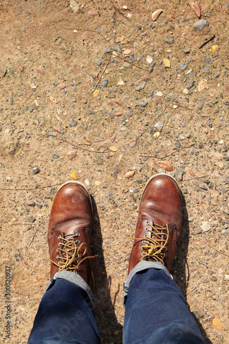 man wearing leather boots standing on country road, close up safty shoes