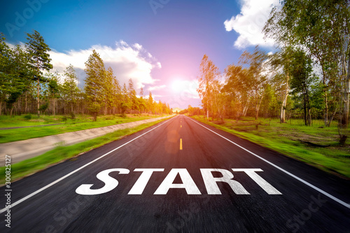 The word start written on highway road in the middle of empty asphalt road at beautiful blue sky.